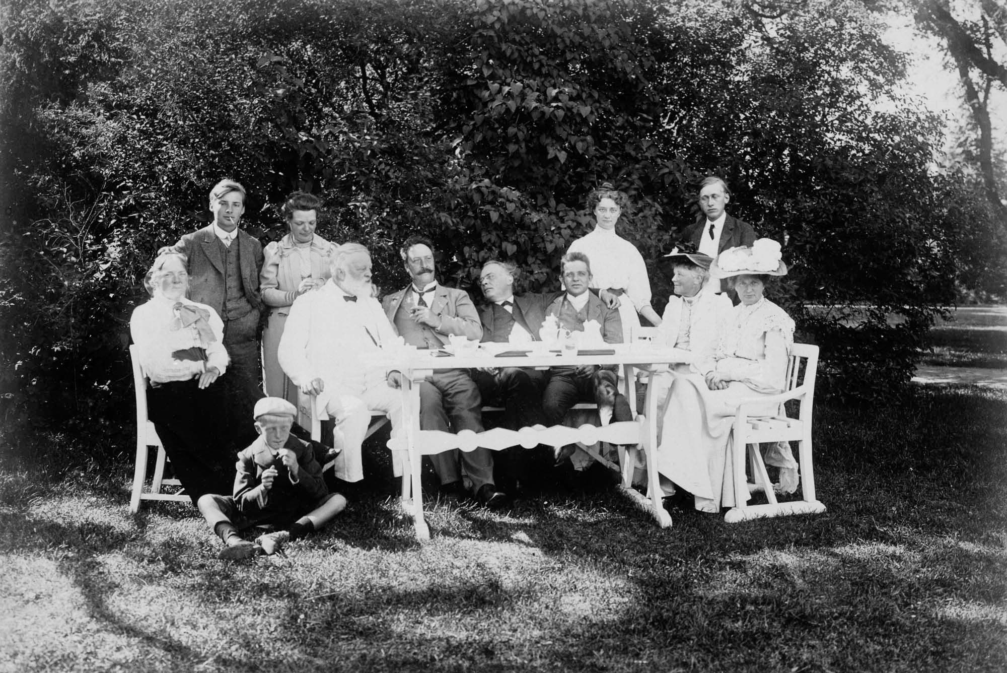 Ved kaffebordet i haven: Anne Marie Carl-Nielsen, Engelbert Röntgen, Mien Röntgen, Viggo Neergaard, Angul Hammerich, Julius Röntgen, Carl Nielsen, Bodil Neergaard, Viggo Neergaards søster Marie, Oluf Hartmann, ukendt dame og i græsset Hans Børge.